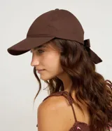 Gorra de sarga marrón con visera curva y detalle de lazo en la parte trasera.