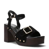 Sandalias negras Miss Carol modelo Torino, con plataforma y taco alto de madera, tira ancha en el empeine con hebilla dorada y tachas decorativas, y tira con hebilla en el tobillo.