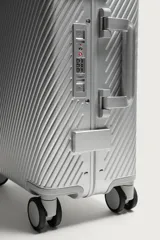 Maleta de cabina rígida fabricada en aluminio con diseño de líneas diagonales en relieve. Cuenta con cuatro ruedas giratorias, cierre TSA, compartimento principal con separador y asa telescópica.