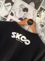 Remera negra de algodón con estampado de dos personajes de anime en blanco y texto "MAKOSH".
