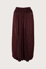 Pantalón de corte holgado estilo bombacho, color bordó con estampado de pequeñas líneas doradas. Presenta cintura elástica fruncida y puños elásticos en los tobillos.