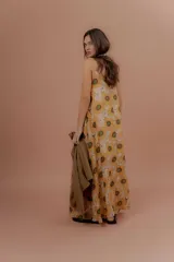 Vestido largo de tirantes finos, con escote en V y estampado de girasoles sobre fondo beige.