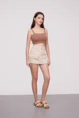Falda corta de jean color beige claro, de corte al cuerpo, con tiro bajo y bolsillos cargo grandes y planos en los laterales.