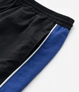 Pantalón deportivo de corte recto confeccionado en microfibra de poliamida, color negro con paneles laterales en color violeta y detalles en blanco. Cuenta con cintura elástica con cordón ajustable.