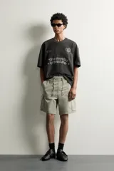 Bermuda cargo color negro de corte relaxed fit, confeccionada en tejido de algodón con elasticidad y efecto lavado. Cuenta con cintura elástica ajustable con cordón, bolsillos frontales y bolsillos laterales tipo cargo con solapa en las perneras.