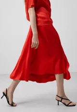 Falda midi color rojo, de viscosa, con corte asimétrico y cierre lateral invisible.