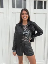 Chaqueta dorada metalizada con cuello camisero, cierre frontal con botones y bolsillos de parche en el pecho.