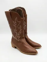 Bota estilo texana de caña alta, confeccionada en cuero sintético color chocolate, con bordados decorativos en hilo blanco y taco bajo cuadrado.