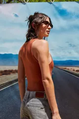 Body color marrón oscuro, confeccionado en microfibra, con escote delantero y trasero cerrado, cuerpo embolsado y gancho corsetero regulable en la entrepierna.