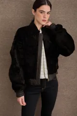 Campera tipo bomber de textura afelpada en color negro, con cierre frontal, cuello alto y puños y ruedo elásticos en cuero.