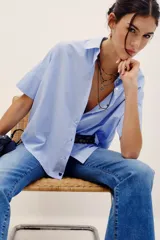 Camisa de manga corta celeste con rayas finas blancas, cuello camisero, cierre frontal con botones y corte amplio.