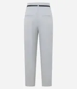 Pantalón zanahoria de vestir color gris claro, con cintura alta, cinturón con hebilla metálica y corte holgado en las caderas que se estrecha en las piernas.