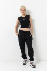 Babucha deportiva de corte holgado, color negro, con cintura elástica ajustable mediante cordones y puños elásticos en los tobillos. Cuenta con bolsillos laterales.