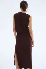 Top sin mangas color marrón oscuro, con cuello redondo y abertura frontal cerrada con tres botones dorados en forma de concha de mar.