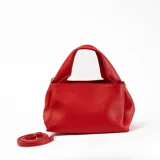 Bandolera roja de cuero sintético con correa larga regulable y asa corta.