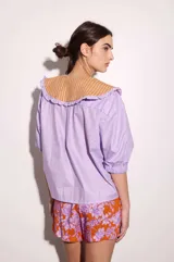Camisa de lino texturado con diseño a rayas verticales rojas y blancas, cuello babero desmontable en color lila con volados y mangas cortas abullonadas.