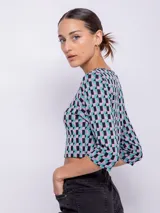 Top corto negro con estampado de líneas onduladas blancas, mangas 3/4 y abertura circular en el pecho.