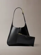Cartera mediana Calvin Klein de poliuretano color negro, diseño estructurado tipo hobo, con correa de hombro ajustable y detalles metálicos dorados.