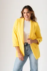 Blazer amarillo de corte entallado, con mangas tres cuartos con botón decorativo, solapas y bolsillos delanteros.