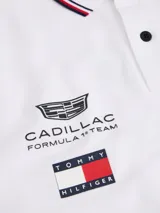 Chomba de corte regular confeccionada en algodón elástico, con cuello polo y cartera de dos botones. Presenta ribetes distintivos en cuello y puños, cinta lateral y múltiples logos bordados que incluyen Tommy Hilfiger, Cadillac Formula 1 Team y Pirelli.