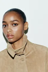 Chaqueta de ante color tostado con cuello solapa, manga larga con puño, bolsillos con solapa en el delantero y cierre frontal con botones.