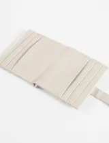 Tarjetero de cuero vegano con acabado brillante, cierre con solapa y broche a presión. Cuenta con ranuras para tarjetas y detalle de logo metálico en la parte frontal.