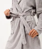 Bata de baño de corte regular confeccionada en tejido fleece suave y abrigado. Presenta capucha, mangas largas, bolsillos frontales y cierre mediante lazo ajustable en la cintura. Posee una textura sutil con diseño de gatitos.