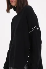 Sweater de cuello alto tipo polera, color negro, con detalle de pespuntes decorativos en color blanco en las mangas y laterales.