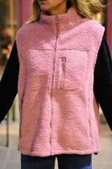 Chaleco de corderito color rosado, con cuello alto, cierre frontal y un bolsillo con cierre en el pecho.