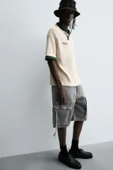 Bermuda de corte relajado en denim de algodón color beige, estilo cargo, con cinco bolsillos y bolsillos plastrón con solapa en las perneras.