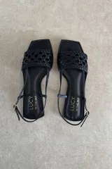 Sandalias chatas de cuero negro, marca Lucy in the Sky, con tira delantera trenzada, puntera cuadrada y tira ajustable al talón.