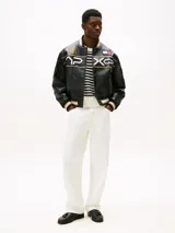 Pantalón jean blanco de corte amplio y pierna recta, con cintura ajustable en la parte trasera. Presenta cierre de cremallera con botón, dos bolsillos delanteros de parche y dos bolsillos traseros ribeteados. Detalles distintivos de la colección APXGP.