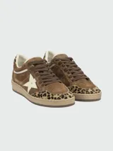 Zapatillas Golden Goose modelo Ball Star, confeccionadas en gamuza marrón con detalles en estampado animal print de leopardo en la puntera y el talón. Presentan una estrella lateral blanca, cordones marrones y suela de goma con efecto desgastado.
