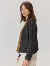 Saco abierto de punto con textura jaspeada en color gris oscuro, con bordes frontales en contraste color marrón. Presenta mangas largas y un corte recto.