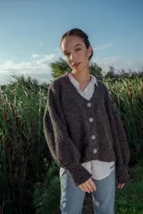 Cárdigan tejido de boucle color gris oscuro, con escote en V, mangas largas abullonadas y cierre frontal con botones grandes. Corte holgado.