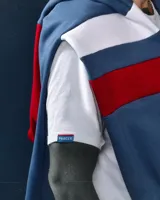 Canguro de felpa azul jean gastado con capucha roja y tiras blancas y rojas en las mangas. Diseño original de autor, corte holgado.