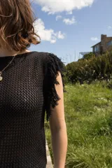 Musculosa tejida color violeta con diseño calado y flecos en los hombros.