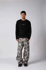 Sweater de punto acanalado con diseño de calce relajado, cuello redondo y mangas largas. Presenta una estampa gráfica pequeña en el centro del pecho y un parche con logo en el puño.