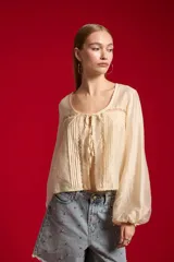 Blusa de lyocell color natural, holgada y de manga larga, con cuello redondo, detalles de encaje y lazo para anudar en el frente.