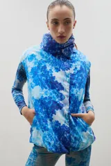 Chaleco puffer con cuello alto y cierre frontal oculto, con estampado forestal en tonos azules.