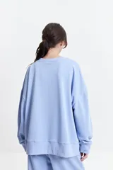 Buzo de felpa color marrón con estampa frontal en rosa, cuello redondo y hombros caídos.