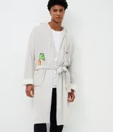 Bata de baño larga para hombre, confeccionada en plush con interior de felpa. Presenta diseño recto con capucha, cierre frontal mediante faja para atar, mangas largas y bolsillos delanteros. Incluye bordados de Bugs Bunny y una zanahoria.