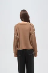 Sweater de algodón color natural, de corte holgado y cuello redondo. Presenta detalles de costuras decorativas con bordado en los hombros y puños acanalados.