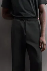 Pantalón jogger relaxed fit Zara Athleticz de tejido técnico compacto elástico con mezcla de algodón. Presenta cintura elástica ajustable con cordón, bolsillos laterales en la cadera, bolsillo trasero con cierre de cremallera, bajo ajustable con elástico y detalle de logo estampado en la pernera.