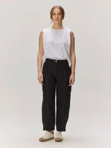 Pantalón de lino color negro con costuras pespunteadas en contraste de color tostado, corte estilo barrel con bolsillos y botón frontal.