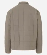 Campera marrón claro para hombre, confeccionada en tejido capitoneado de poliéster. Tiene cuello polo, manga larga con puños ajustados, abotonado delantero y bolsillo en el pecho.