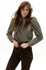 Camisa de manga larga confeccionada en popelina de algodón, con estampado geométrico en tonos verdes y negros. Presenta cuello clásico camisero, hombros ligeramente abullonados y cierre frontal con botones de nácar.