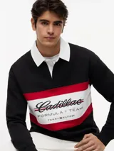 Chomba de rugby de manga larga Tommy Hilfiger en colaboración con Cadillac Formula 1 Team. Presenta un diseño en bloques de color negro, blanco y rojo, con cuello estilo rugby en color blanco y cierre frontal oculto. Incluye el logo de Cadillac en fuente script y el logo de Tommy Hilfiger estampados en el pecho.