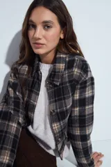 Campera de paño con diseño de cuadros en tonos negro, gris y beige. Presenta cuello camisero, cierre frontal con botones y corte corto.