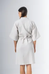 Bata kimono corta color beige, confeccionada en tela waffle de algodón. Tiene mangas al codo, lazo de ajuste en la cintura y detalle de vivo en la solapa.